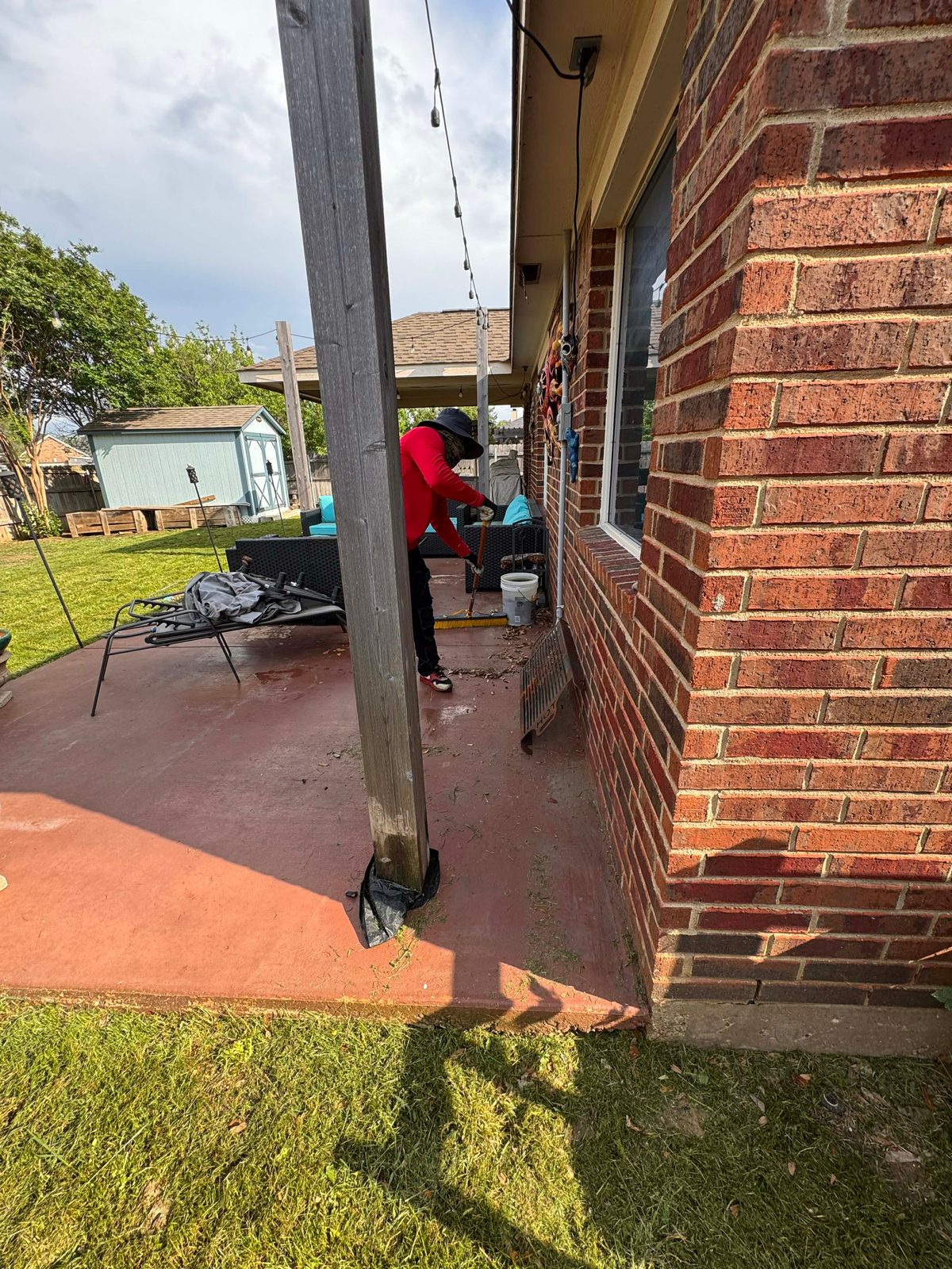 HP Helpers worker sweeping winter debris off a residential patio